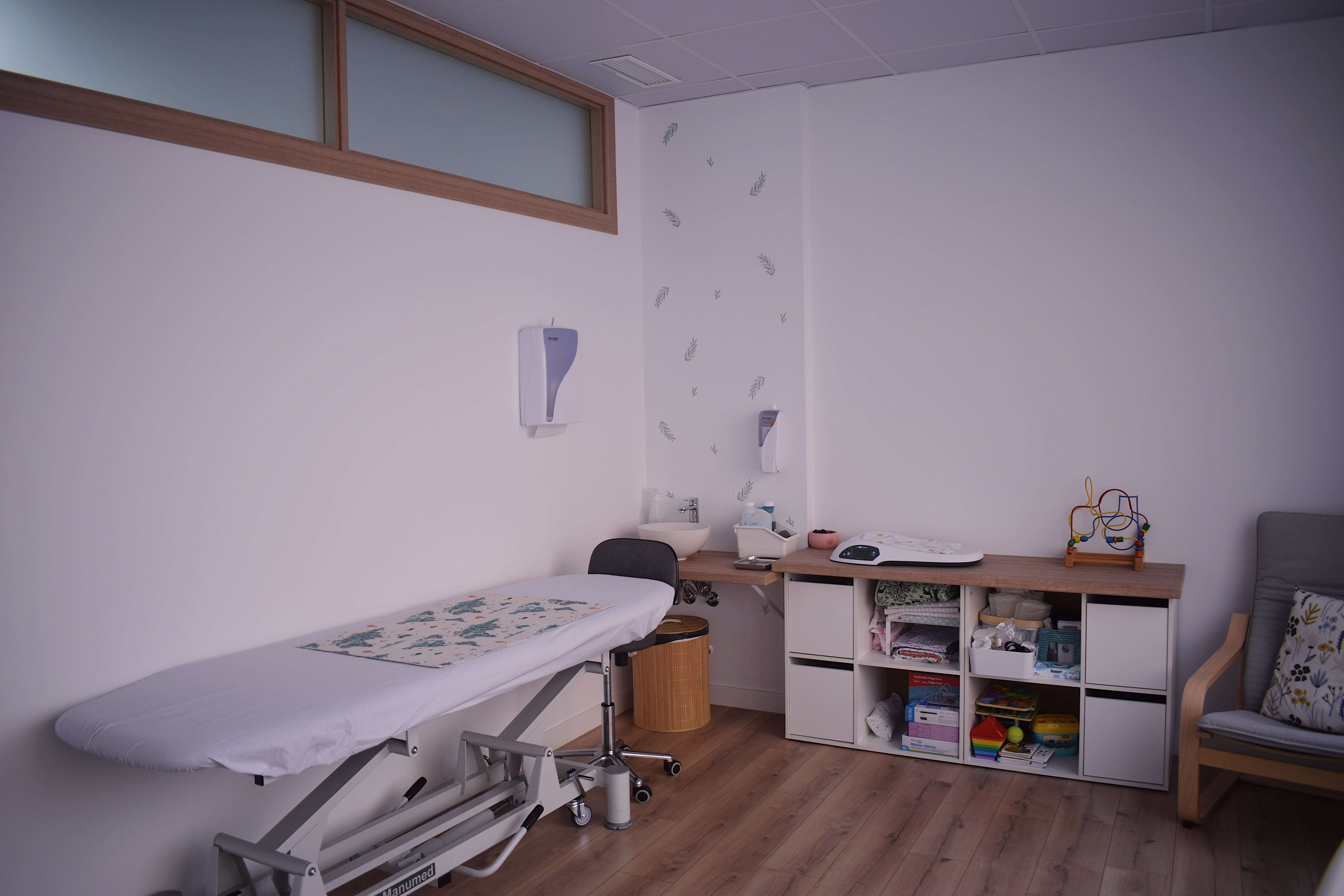Sala de tratamiento con camilla, lavabo, mueble con material sanitario y un sillón